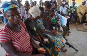Residents of a quarantined community in Sierra Leone sit in a crowded treatment center